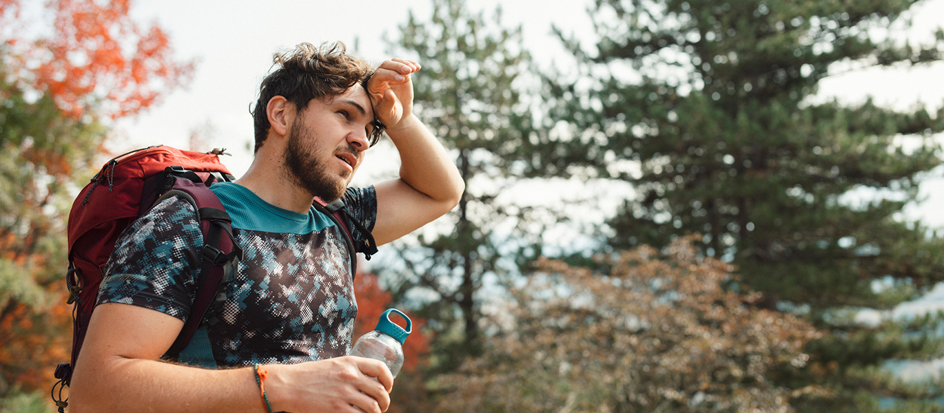 Man feeling overheated on walk with a water bottle