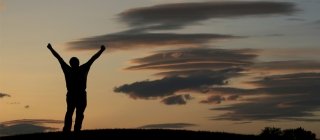 Man celebrating on a mountain at dusk