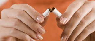 A person breaking a cigarette in half for quitting smoking