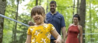 Girl playing in the woods with her parents