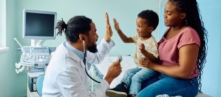 boy giving high five to his pediatrician after medical examination at doctor's office