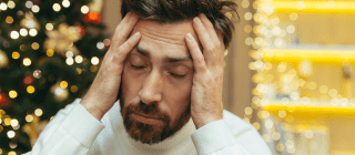 Stressed out man holding his head with holiday decorations in the background