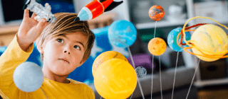 young boy playing with space-themed toys