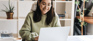 young woman looking at laptop with book shelf behind her