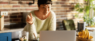 Woman standing in kitchen using laptop on a virtual nutritional counseling call 