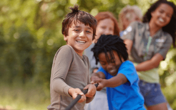 group of kids playing tug of war with a rope outside